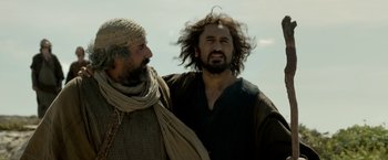Movie still from “Risen” (2016), directed by Kevin Reynolds – Two men standing next to each other on a beach; Medium shot, Low angle