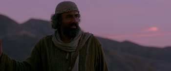 Movie still from “Risen” (2016), directed by Kevin Reynolds – A man with long hair and a beard is wearing a hat; Medium shot, Low angle