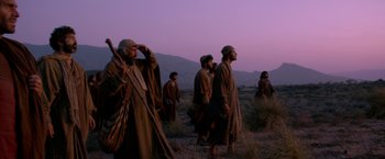 Movie still from “Risen” (2016), directed by Kevin Reynolds – A group of men standing on top of a grass covered field; Wide shot, Low angle