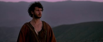 Movie still from “Risen” (2016), directed by Kevin Reynolds – A man standing on top of a hill with a mountain in the background; Close Up shot, Low angle