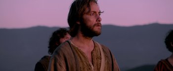 Movie still from “Risen” (2016), directed by Kevin Reynolds – A man with long hair and a beard standing in a field; Close Up shot, Low angle