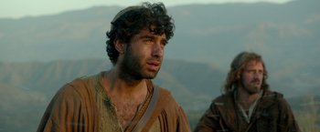 Movie still from “Risen” (2016), directed by Kevin Reynolds – A man with curly hair is looking into the distance; Close Up shot, Over the shoulder angle
