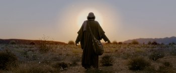 Movie still from “Risen” (2016), directed by Kevin Reynolds – A person walking through a field with a bag; Wide shot, Low angle