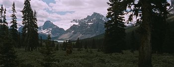 Movie still from “River of No Return” (1954), directed by Otto Preminger – A man riding a horse through a field with a mountain in the background; Extreme Wide shot, Low angle