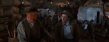 Movie still from “River of No Return” (1954), directed by Otto Preminger – A man in a cowboy hat walking through a crowd of people; Medium shot, Low angle