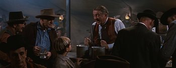 Movie still from “River of No Return” (1954), directed by Otto Preminger – A man and a boy are holding buckets and talking; Medium shot, Over the shoulder angle