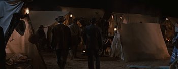 Movie still from “River of No Return” (1954), directed by Otto Preminger – A group of men walking in the dirt at night; Wide shot, High angle