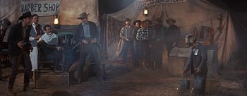 Movie still from “River of No Return” (1954), directed by Otto Preminger – A group of men standing in front of a tent; Wide shot, Low angle