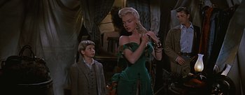 Movie still from “River of No Return” (1954), directed by Otto Preminger – A woman in a green dress standing next to a young boy; Medium shot, Low angle