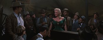 Movie still from “River of No Return” (1954), directed by Otto Preminger – A woman in a green dress standing in front of a piano; Medium shot, Low angle
