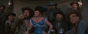 Movie still from “River of No Return” (1954), directed by Otto Preminger – A group of people sitting at a table with a woman; Medium shot, Low angle