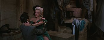 Movie still from “River of No Return” (1954), directed by Otto Preminger – A woman in a green dress holding a man in a black suit; Medium shot, Over the shoulder angle