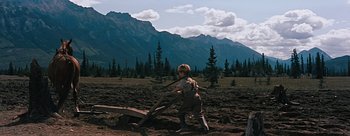 Movie still from “River of No Return” (1954), directed by Otto Preminger – A young boy in overalls is standing in a field with mountains in the background; Wide shot, High angle