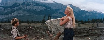 Movie still from “River of No Return” (1954), directed by Otto Preminger – A woman holding onto a blanket in a field; Medium shot, Low angle