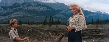 Movie still from “River of No Return” (1954), directed by Otto Preminger – A woman holding a stick in front of a tree stump; Medium shot, Low angle