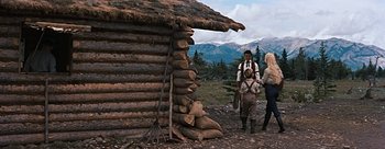 Movie still from “River of No Return” (1954), directed by Otto Preminger – A group of people standing next to a log cabin; Wide shot, Over the shoulder angle