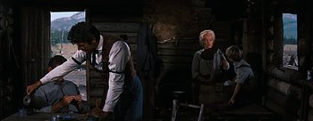 Movie still from “River of No Return” (1954), directed by Otto Preminger – A man and a woman standing next to each other in front of a fireplace; Medium shot, Over the shoulder angle