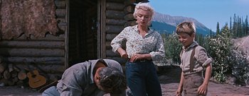 Movie still from “River of No Return” (1954), directed by Otto Preminger – A woman standing next to a man in a field; Wide shot, Low angle