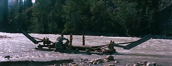 Movie still from “River of No Return” (1954), directed by Otto Preminger – A man on a raft in the middle of a river; Extreme Wide shot, High angle