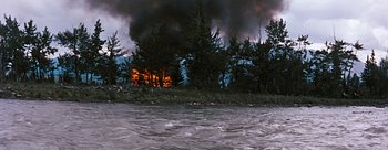 Movie still from “River of No Return” (1954), directed by Otto Preminger – A house on fire next to a body of water; Extreme Wide shot, High angle