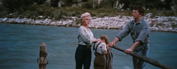 Movie still from “River of No Return” (1954), directed by Otto Preminger – A woman and a child standing next to a body of water; Wide shot, High angle