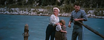 Movie still from “River of No Return” (1954), directed by Otto Preminger – A woman standing next to a child near a body of water; Wide shot, Over the shoulder angle