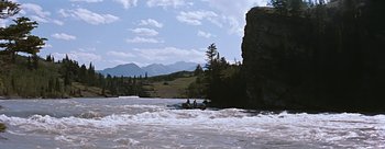 Movie still from “River of No Return” (1954), directed by Otto Preminger – Two people on a raft in a body of water near mountains; Extreme Wide shot, High angle