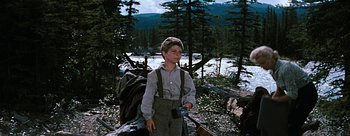 Movie still from “River of No Return” (1954), directed by Otto Preminger – A young boy standing in the woods holding a camera; Medium shot, Low angle