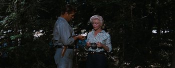 Movie still from “River of No Return” (1954), directed by Otto Preminger – A man and a woman standing next to each other in the woods; Medium shot, Low angle