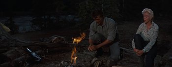 Movie still from “River of No Return” (1954), directed by Otto Preminger – A man lighting a fire in the woods; Medium shot, High angle