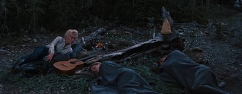 Movie still from “River of No Return” (1954), directed by Otto Preminger – Two people laying on the ground next to a campfire; Wide shot, High angle