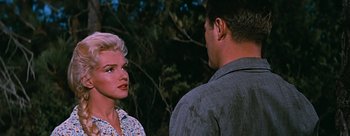 Movie still from “River of No Return” (1954), directed by Otto Preminger – A man and a woman standing next to each other in front of a tree; Close Up shot, Over the shoulder angle