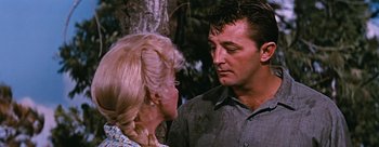 Movie still from “River of No Return” (1954), directed by Otto Preminger – A man and a woman standing next to each other in front of a tree; Close Up shot, Over the shoulder angle