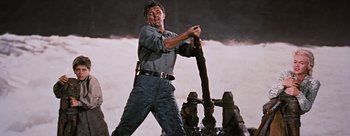 Movie still from “River of No Return” (1954), directed by Otto Preminger – A man holding onto a fire hydrant while standing in front of a fire hydrant; Medium shot, Low angle