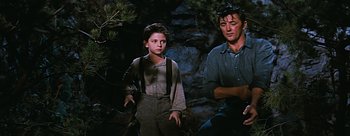Movie still from “River of No Return” (1954), directed by Otto Preminger – A man and a young boy standing next to each other in front of rocks; Medium shot, Low angle