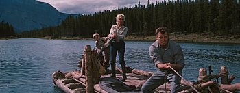 Movie still from “River of No Return” (1954), directed by Otto Preminger – A woman standing on a raft with two men; Wide shot, Low angle