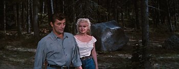 Movie still from “River of No Return” (1954), directed by Otto Preminger – A man and a woman walking through the woods; Medium shot, Low angle