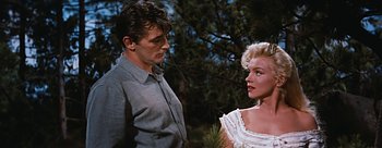 Movie still from “River of No Return” (1954), directed by Otto Preminger – A man and a woman standing next to each other in front of a tree; Medium shot, Low angle