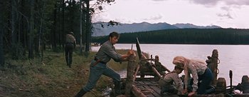 Movie still from “River of No Return” (1954), directed by Otto Preminger – A man is cutting a log on a raft; Wide shot, Low angle