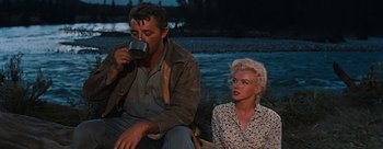 Movie still from “River of No Return” (1954), directed by Otto Preminger – A man and a woman sitting next to each other; Medium shot, Low angle