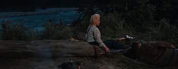 Movie still from “River of No Return” (1954), directed by Otto Preminger – A woman sitting on the ground near a fire pit; Wide shot, High angle