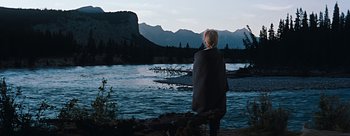 Movie still from “River of No Return” (1954), directed by Otto Preminger – A person standing near a body of water; Wide shot, Over the shoulder angle