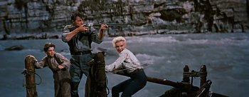 Movie still from “River of No Return” (1954), directed by Otto Preminger – A man and a woman are holding guns in their hands; Medium shot, Low angle