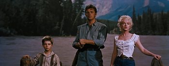Movie still from “River of No Return” (1954), directed by Otto Preminger – A man standing next to two other people in a field; Medium shot, Low angle