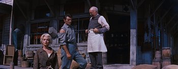 Movie still from “River of No Return” (1954), directed by Otto Preminger – Two men standing next to each other in front of a building; Medium shot, Over the shoulder angle