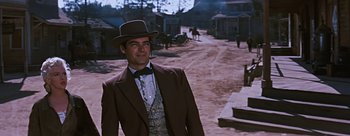 Movie still from “River of No Return” (1954), directed by Otto Preminger – A man wearing a suit and hat standing on a dirt road; Medium shot, Low angle