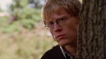 Movie still from “Road Trip” (2000), directed by Todd Phillips – A man with glasses is leaning against a tree; Close Up shot, Over the shoulder angle