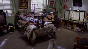 Movie still from “Road Trip” (2000), directed by Todd Phillips – Two men sitting on a bed playing a guitar; Wide shot, High angle