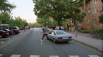 Movie still from “Road Trip” (2000), directed by Todd Phillips – A person running down a street next to a parked car; Wide shot, High angle