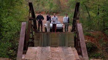 Movie still from “Road Trip” (2000), directed by Todd Phillips – A group of people standing on a bridge over a river; Extreme Wide shot, High angle